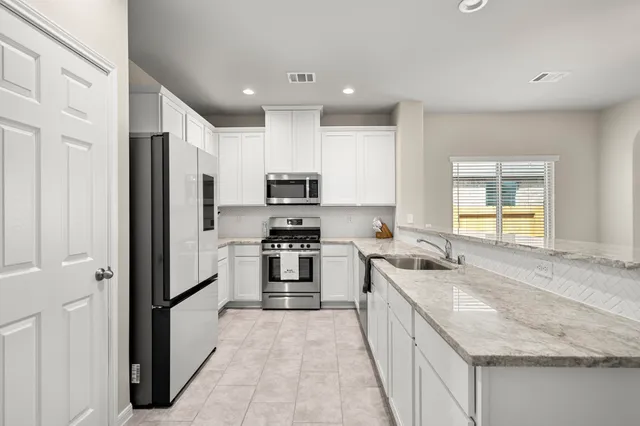 a kitchen with stainless steel appliances granite countertop a sink stove and refrigerator
