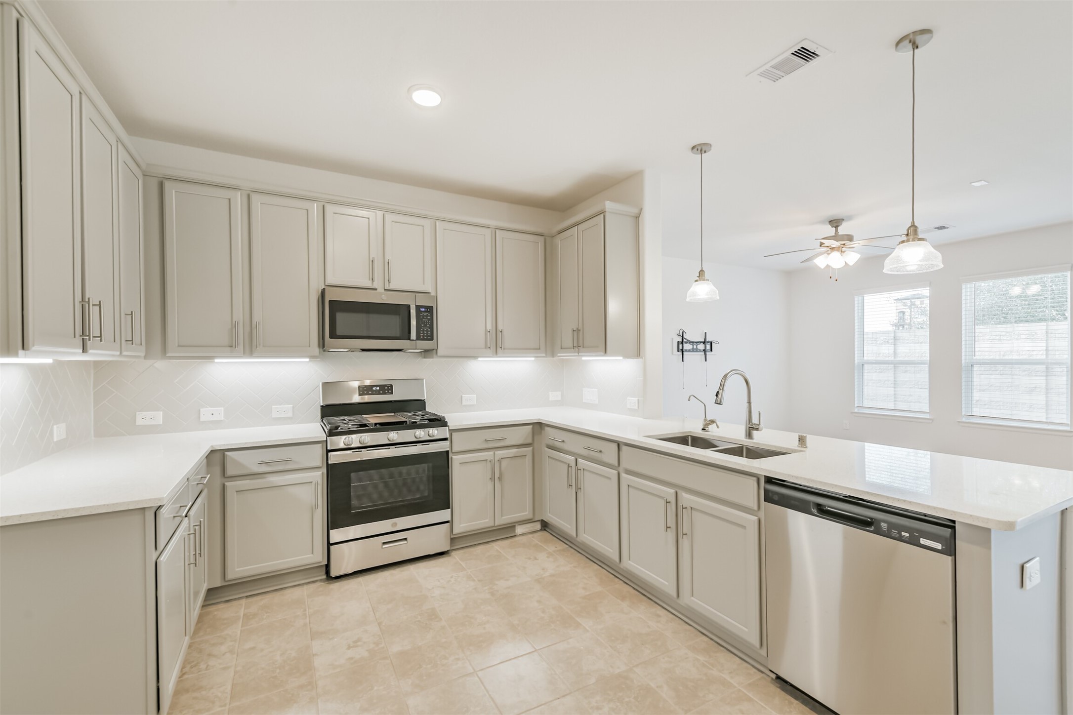 2129 Solstice Boulevard Spring, TX 77386 - Photo 16 of 43 Beautiful, bright kitchen with upgraded cabinetry, stainless steel appliances, and a brand-new dishwasher and cook range. Features a large wraparound counter, tile backsplash, pendant lighting, and an oversized island with double sinks. Open to the living and dining areas for easy entertaining.