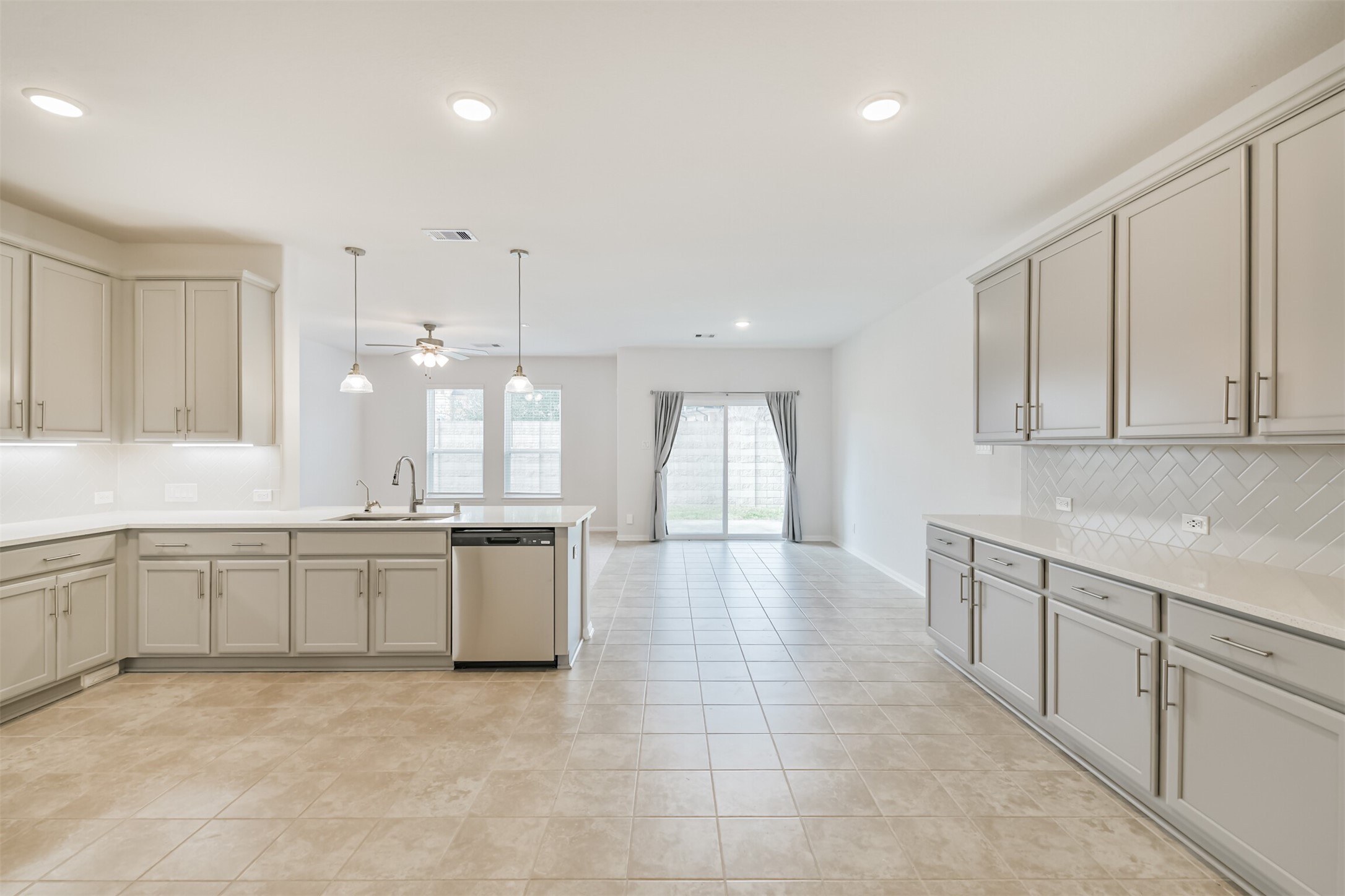 2129 Solstice Boulevard Spring, TX 77386 - Photo 17 of 43 Spacious open-concept kitchen and dining area featuring expansive cabinetry, generous counter space, stainless steel appliances, and a large island overlooking the living room. Tile flooring runs throughout for easy maintenance, and sliding doors offer direct access to the backyard. Bright, airy, and perfect for everyday living or entertaining.
