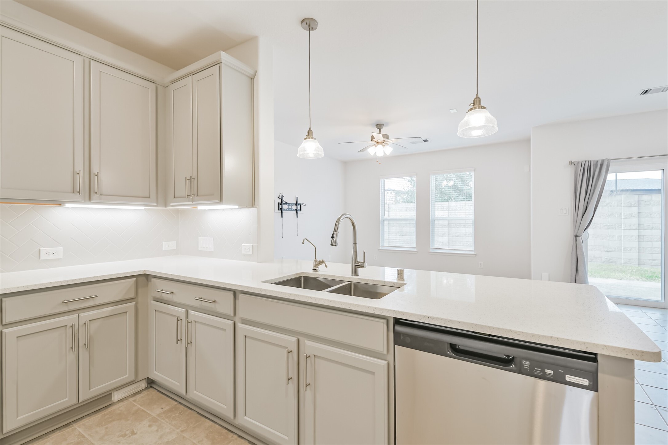 2129 Solstice Boulevard Spring, TX 77386 - Photo 20 of 43 Beautiful kitchen featuring light cabinetry, quartz-style countertops, stainless steel appliances, and a spacious island with double sinks. Pendant lighting and under-cabinet lights brighten the space, while the open layout flows seamlessly into the living and dining areas.