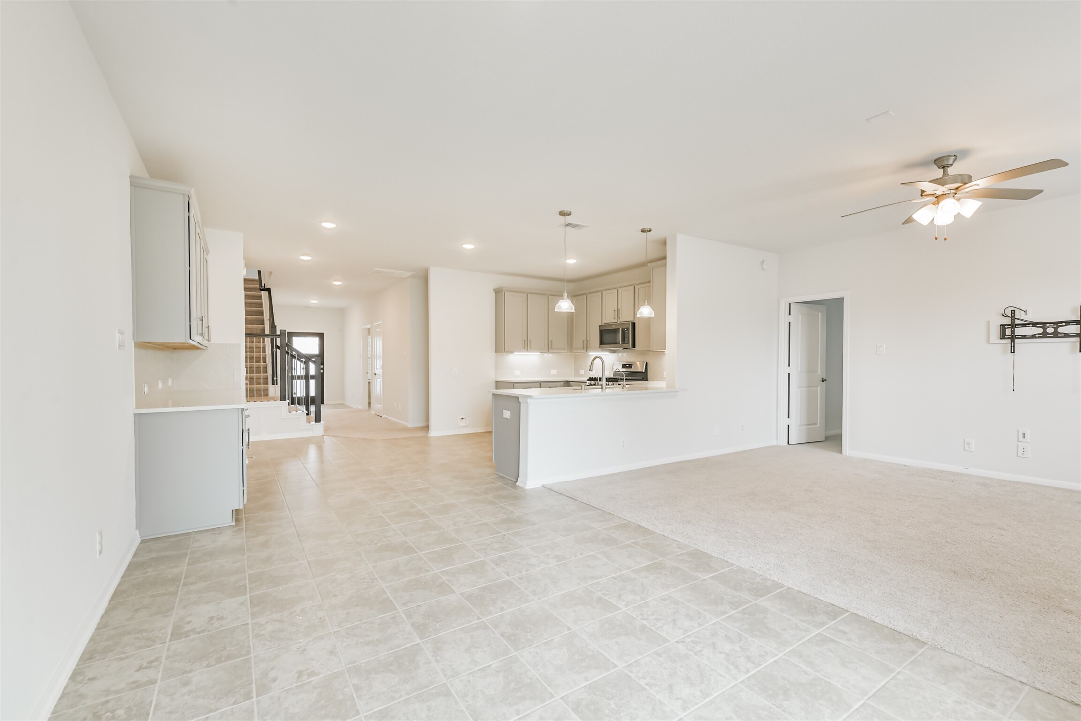 2129 Solstice Boulevard Spring, TX 77386 - Photo 23 of 43 Bright and open living space featuring neutral tile flooring, fresh paint, and great natural light. The kitchen overlooks the family room and offers quartz-style counters, stainless steel appliances, pendant lighting, and plenty of cabinet storage. The open-concept layout flows beautifully from the kitchen to the dining and living areas, making it perfect for everyday living and entertaining.