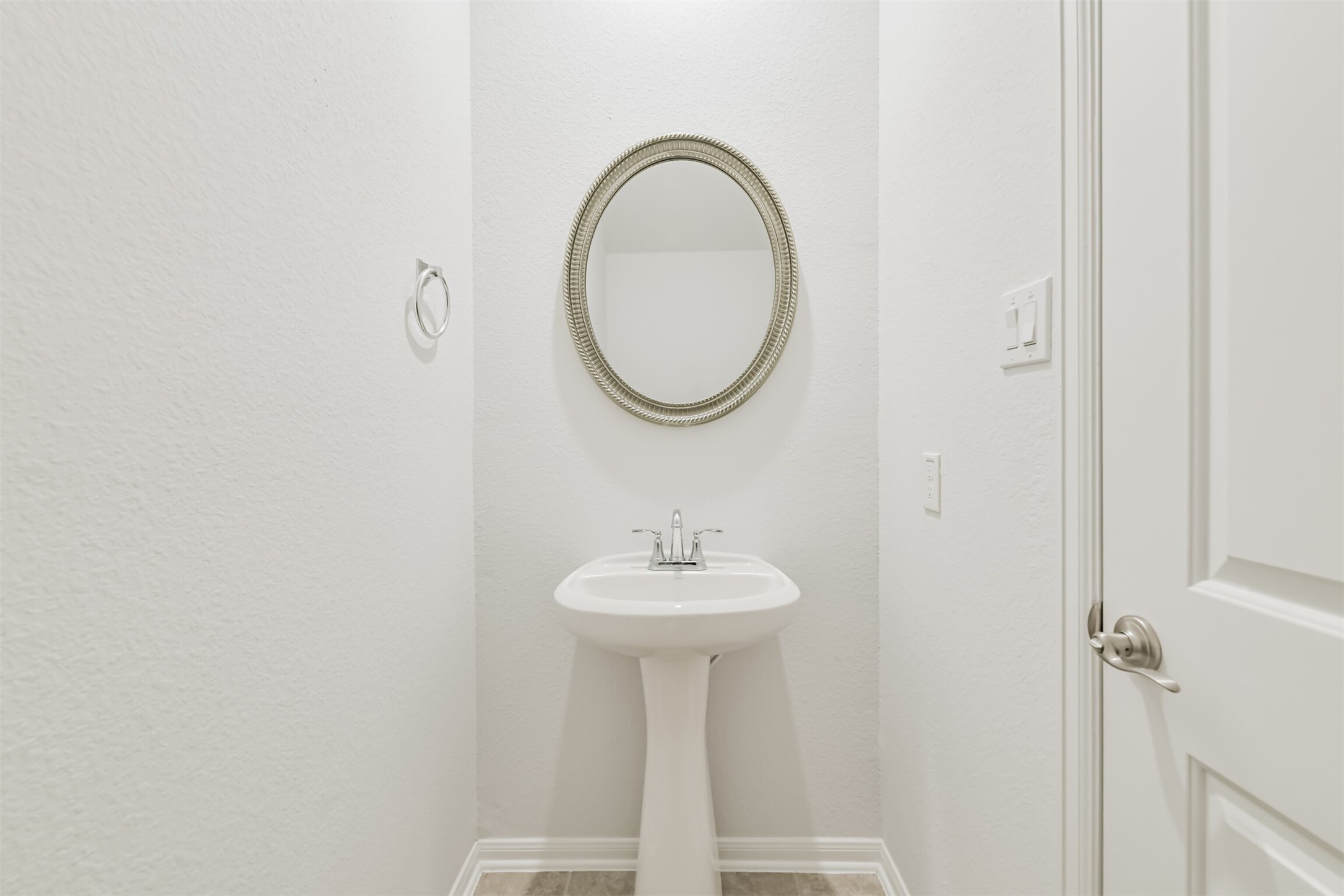2129 Solstice Boulevard Spring, TX 77386 - Photo 24 of 43 Bright and tidy powder bath featuring a pedestal sink, modern fixtures, and a decorative round mirror. The neutral finishes make this space feel fresh and inviting.