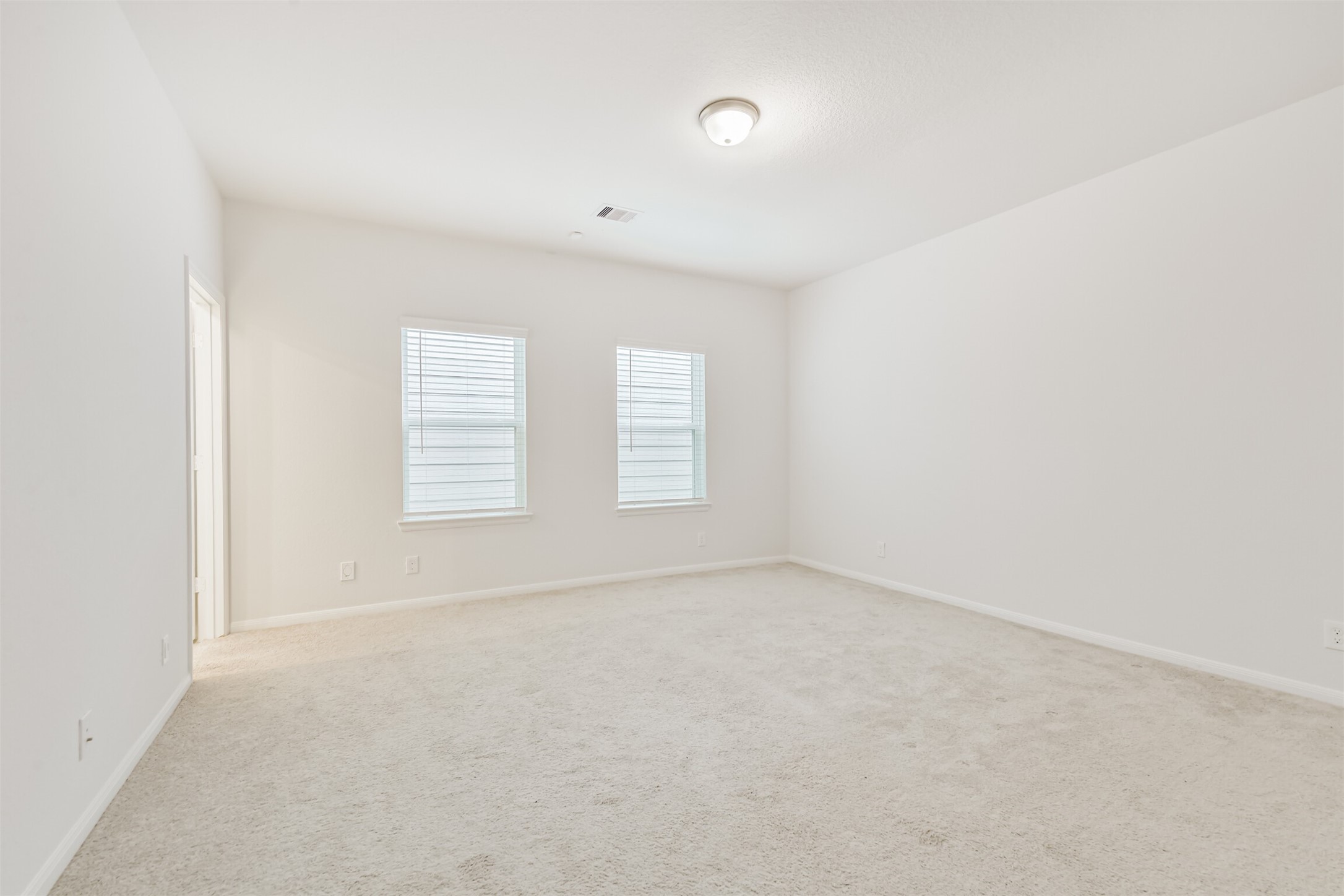 2129 Solstice Boulevard Spring, TX 77386 - Photo 25 of 43 Primary Bedroom (Alternate View):
Bright and spacious primary suite with soft neutral carpet and twin windows that fill the room with natural light. A peaceful layout with direct access to the en-suite bathroom.