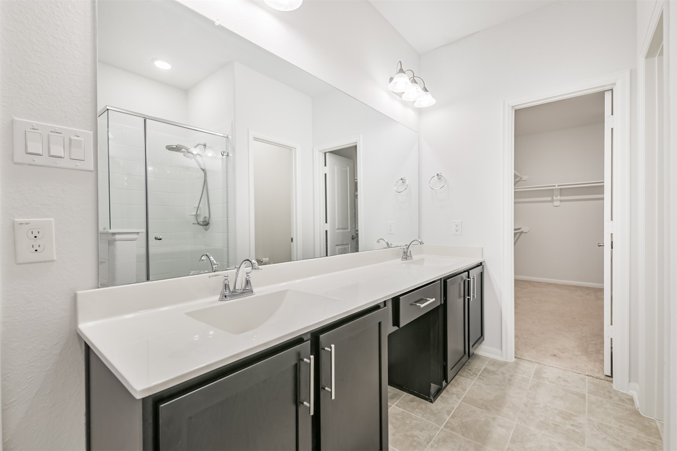 2129 Solstice Boulevard Spring, TX 77386 - Photo 27 of 43 Primary Bathroom (Additional View):
Another view of the spacious primary bath featuring a long double-sink vanity, modern fixtures, and neutral tile flooring. Easy access to both the glass-enclosed shower and the large walk-in closet for added convenience.