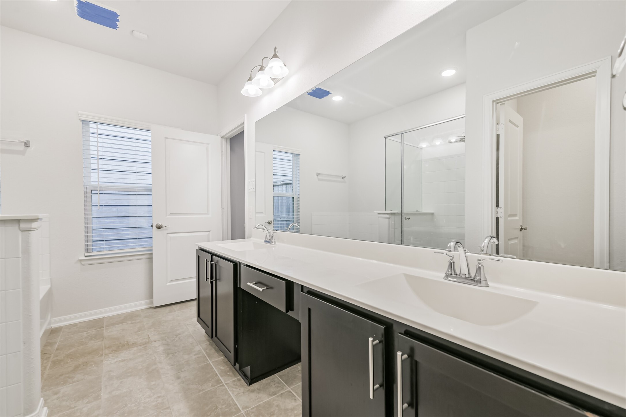 2129 Solstice Boulevard Spring, TX 77386 - Photo 28 of 43 Primary Bathroom (Alternate View):
Spacious primary bath featuring a long double-sink vanity with ample storage, updated fixtures, and great natural light. Neutral tile flooring and a large mirror create an open, airy feel, complemented by the separate soaking tub and glass-enclosed shower.