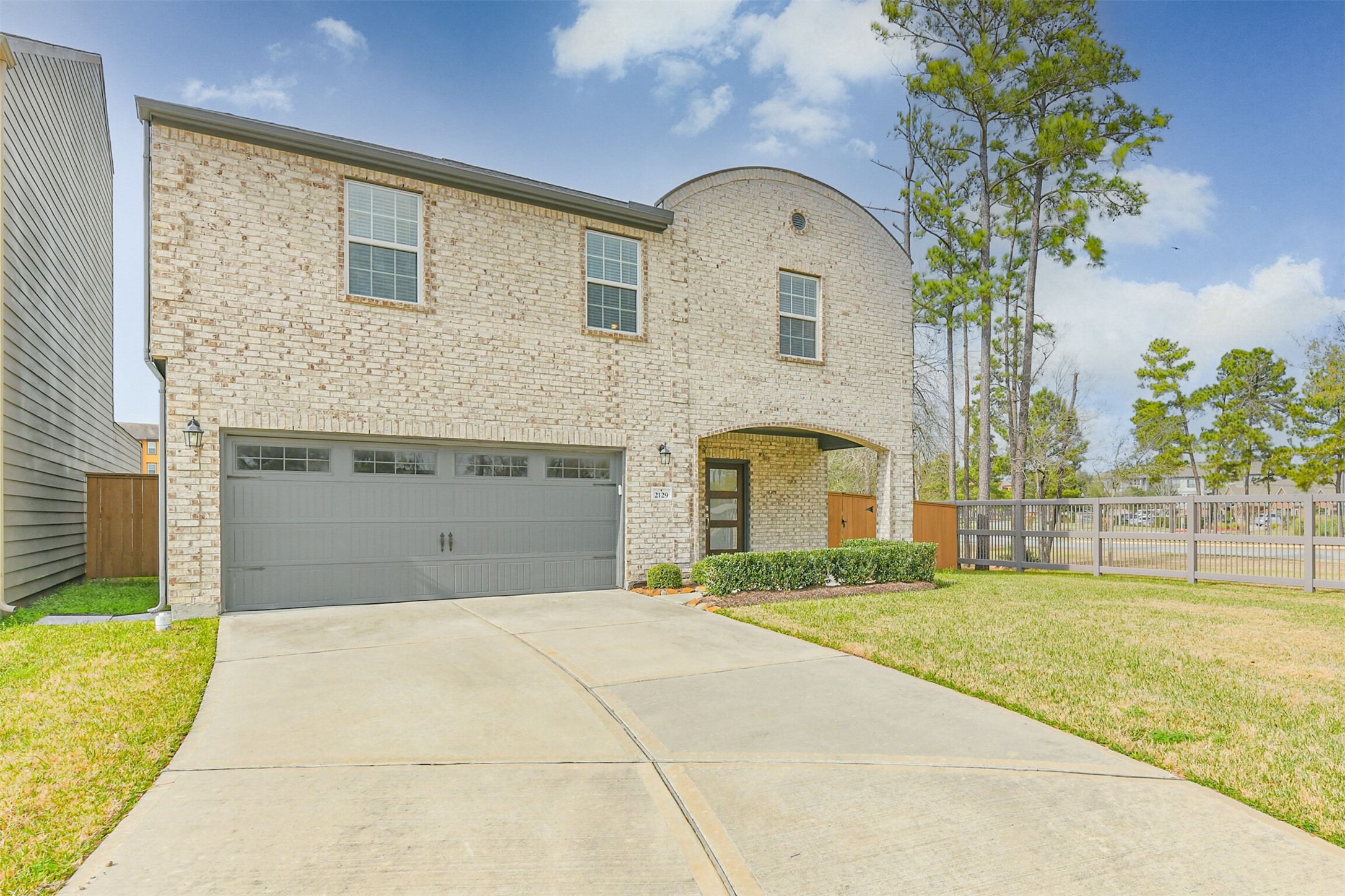 2129 Solstice Boulevard Spring, TX 77386 - Photo 3 of 43 Lovely brick exterior with a welcoming covered entry and modern front door. Wide driveway leading to a spacious two-car garage. Large front yard with manicured landscaping and a side gate that offers easy access to the backyard. Mature trees along the side add privacy and a natural backdrop.