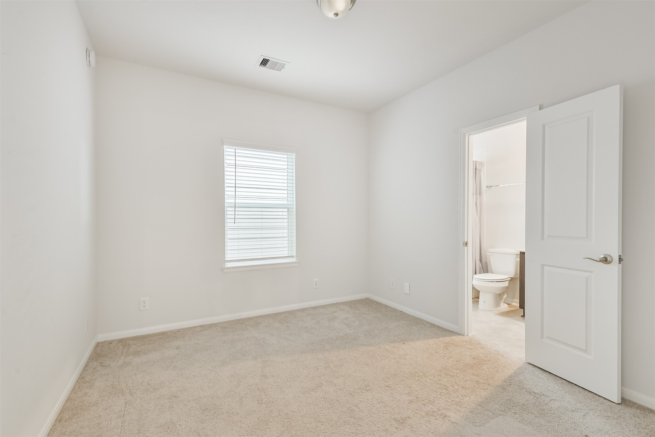 2129 Solstice Boulevard Spring, TX 77386 - Photo 31 of 43 Bedroom with En-Suite Bath:
Comfortable secondary bedroom featuring neutral paint, soft carpet, and a bright window for natural light. Direct access to a private en-suite bathroom makes this an ideal guest room or teen suite.