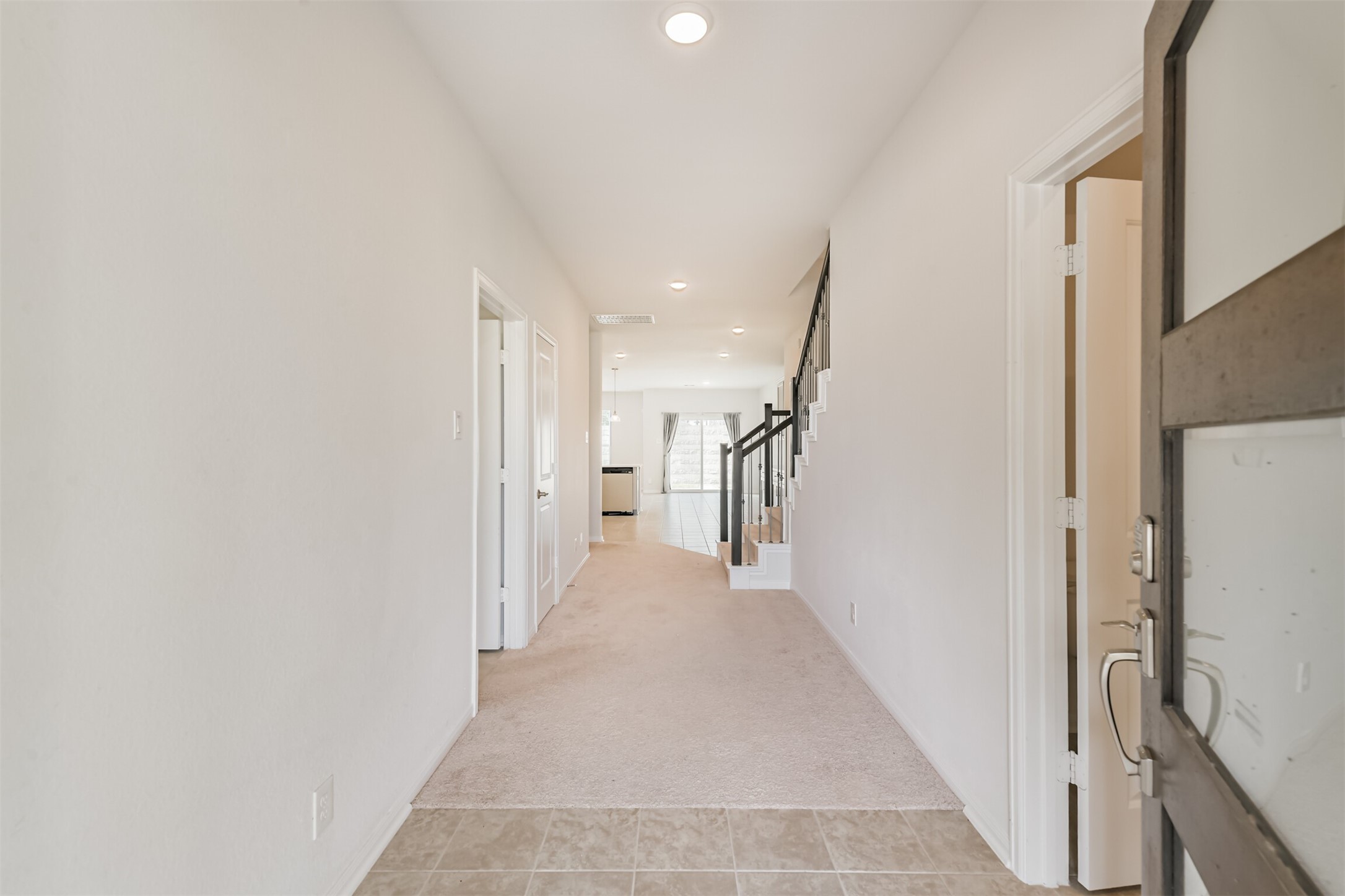 2129 Solstice Boulevard Spring, TX 77386 - Photo 9 of 43 Bright and inviting entryway with neutral tones and an open sightline into the main living areas. Features tile flooring at the front, a spacious hallway, and easy access to downstairs rooms. Modern staircase with iron spindles leads to the second floor.