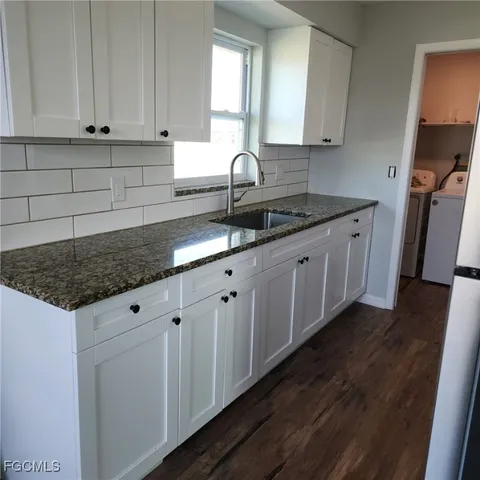 a kitchen with granite countertop white cabinets and sink
