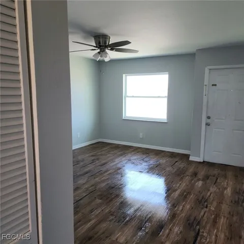 an empty room with wooden floor closet and windows