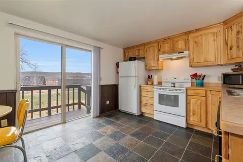 a kitchen with a refrigerator a stove top oven cabinetry and a dining table