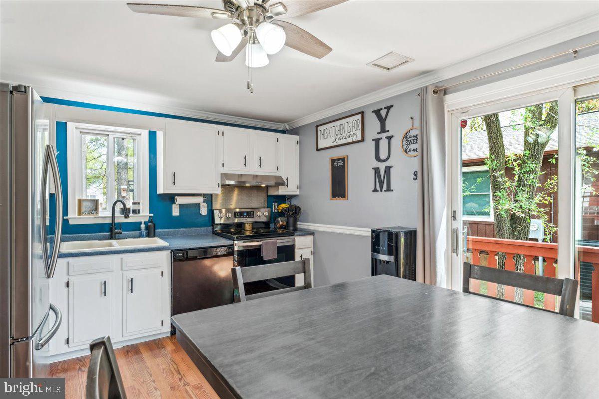 5519 Baskin Street Churchton, MD 20733 - Photo 6 of 20 a kitchen with stainless steel appliances granite countertop a stove top oven a sink dishwasher a dining table and chairs with wooden floor