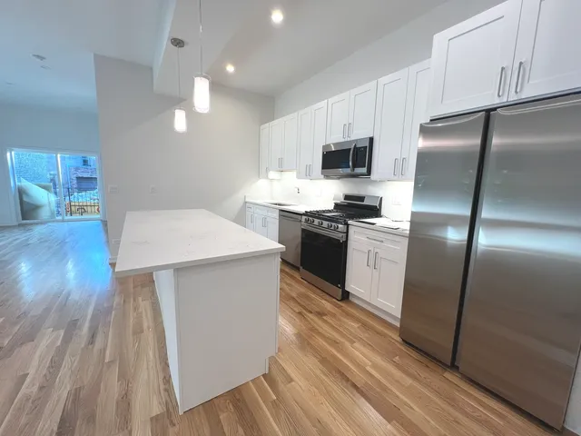 a kitchen with stainless steel appliances a refrigerator a stove a sink and white cabinets