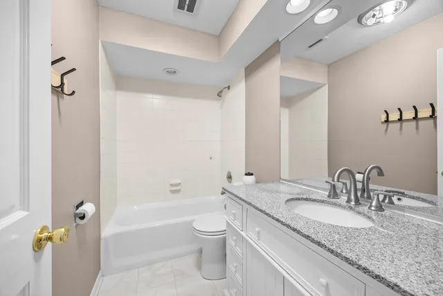 a bathroom with a granite countertop sink a toilet and shower
