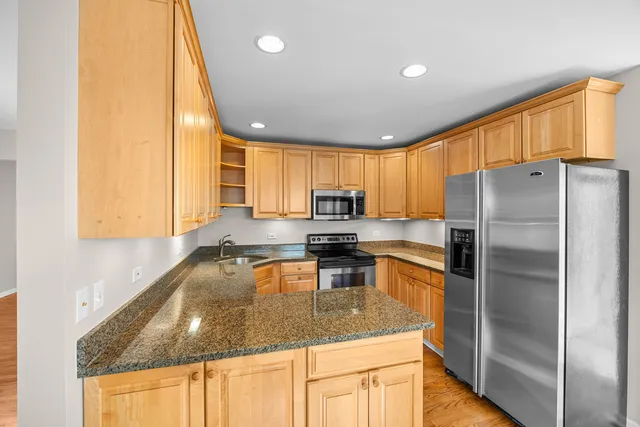a kitchen with granite countertop a refrigerator a sink a stove a dining table and chairs
