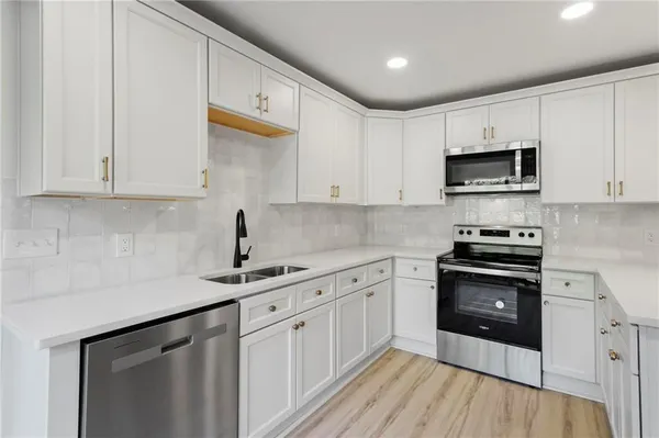 a kitchen with stainless steel appliances granite countertop a sink dishwasher a stove and a microwave oven with cabinets