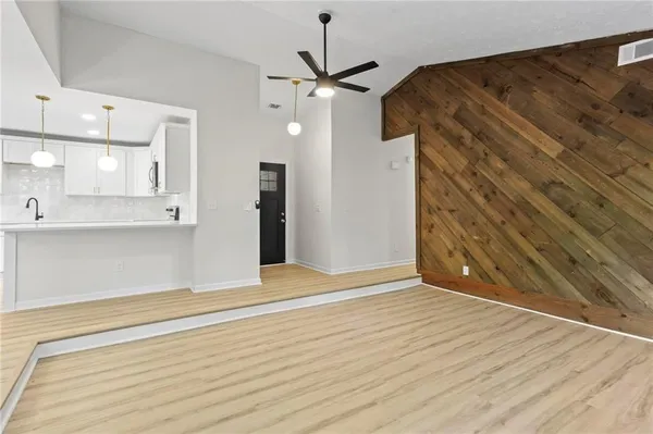 a view of an empty room with wooden floor and a ceiling fan