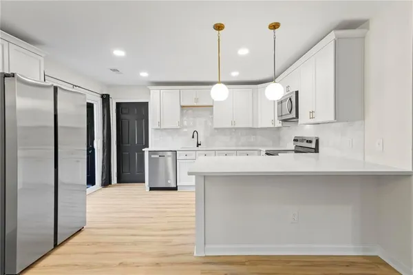 a kitchen with stainless steel appliances kitchen island a refrigerator sink and cabinets