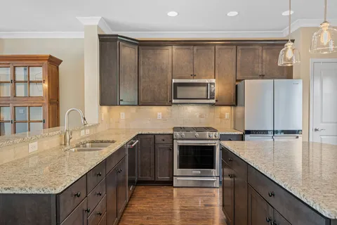 a kitchen with kitchen island granite countertop a sink stove and refrigerator