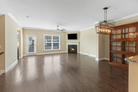an empty room with wooden floor fireplace and windows