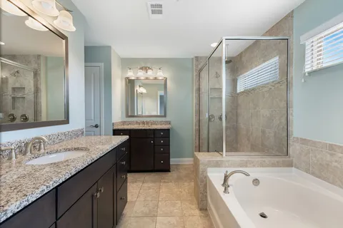 a bathroom with a granite countertop tub sink shower and mirror