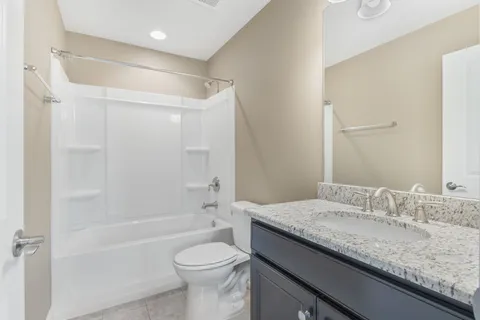a bathroom with a granite countertop sink a toilet and shower