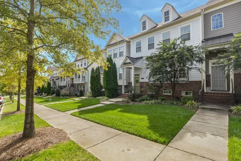 a view of a white house next to a yard with big trees