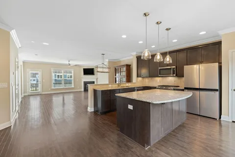 a kitchen with kitchen island a stove a sink a refrigerator and white cabinets with wooden floor