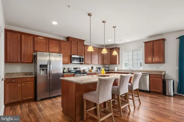 a kitchen with granite countertop a center island stainless steel appliances cabinets and wooden floor