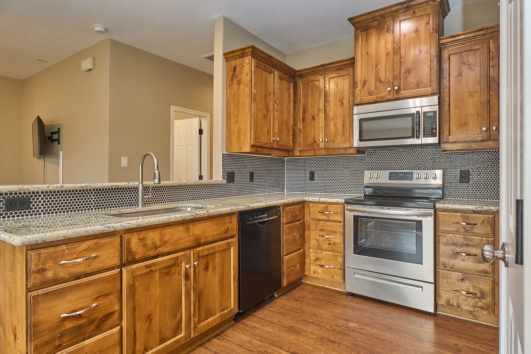 1807 Nuches Lane Bryan, TX 77803 - Photo 8 of 27 This kitchen features rustic wooden cabinets, stainless steel appliances, and a modern tile backsplash. It offers ample countertop space with a sleek, integrated sink and a warm, inviting atmosphere.