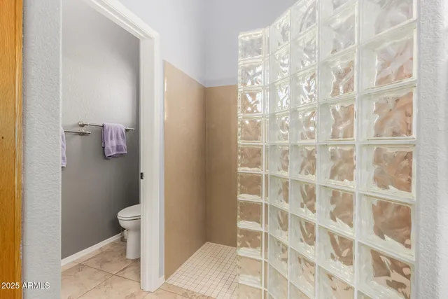 a bathroom with a granite countertop sink a mirror a shower and a toilet