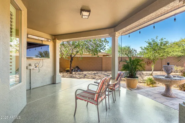 a backyard of a house with table and chairs under an umbrella