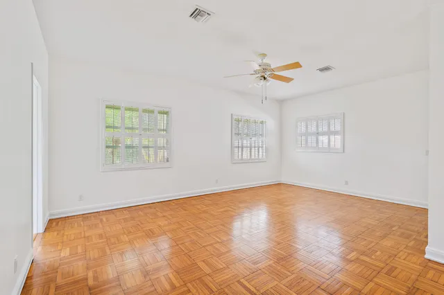 an empty room with windows and ceiling fan