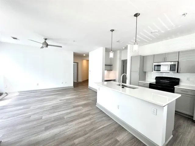 a large kitchen with cabinets wooden floor and a window