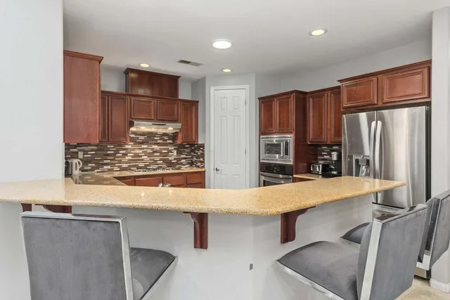 a kitchen with stainless steel appliances kitchen island granite countertop a refrigerator and a stove top oven