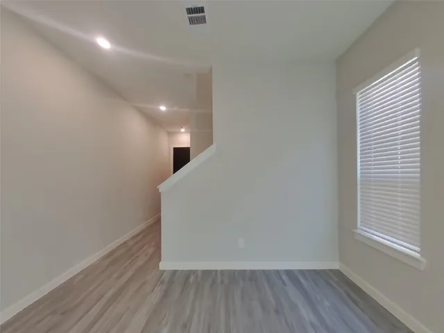a view of hallway with window and wooden floor