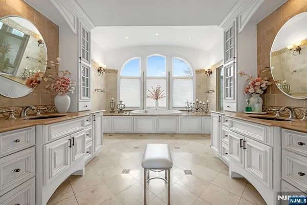 a spacious bathroom with a tub a double vanity sink and mirror