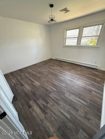 an empty room with wooden floor ceiling fan and windows
