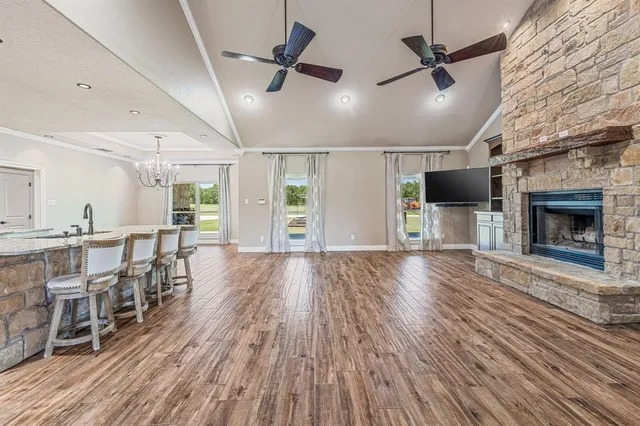 an empty room with wooden floor fireplace and windows