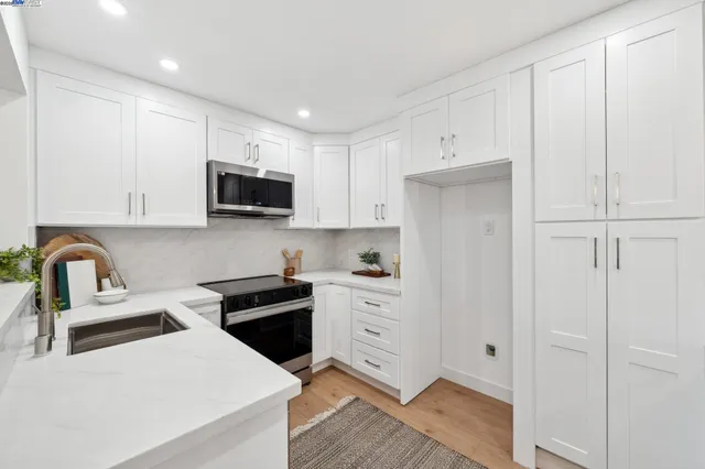 a kitchen with white cabinets and black appliances