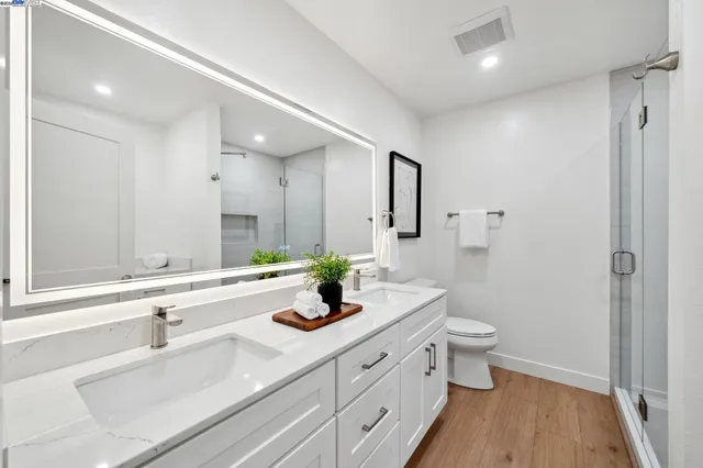 a bathroom with a double vanity sink a toilet and a large mirror