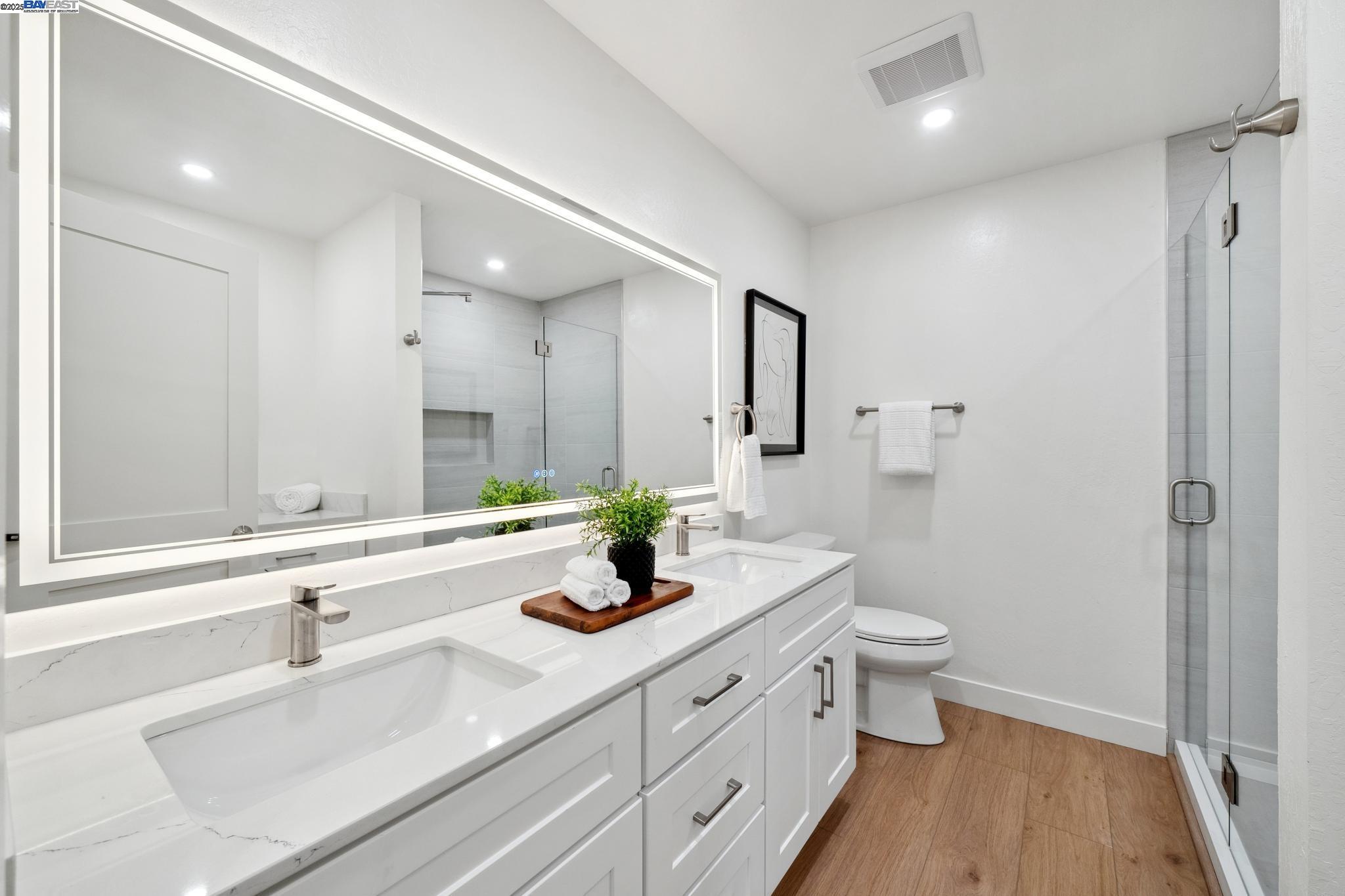 4033 Terra Granada Drive, Unit 5C Walnut Creek, CA 94595 - Photo 23 of 44 a bathroom with a double vanity sink a toilet and a large mirror