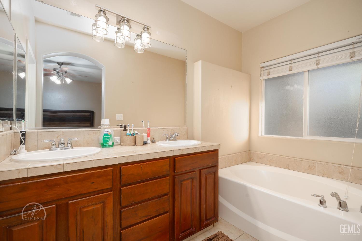 Undisclosed Address Bakersfield, CA 93312 - Photo 15 of 20 a bathroom with a tub a sink and mirror