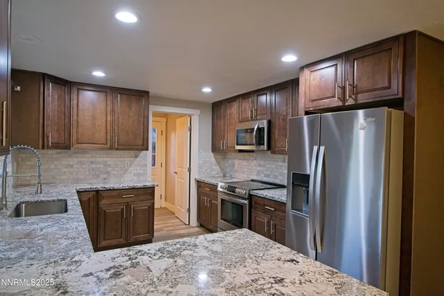 a kitchen with stainless steel appliances granite countertop a refrigerator a stove a sink a oven with wooden floor