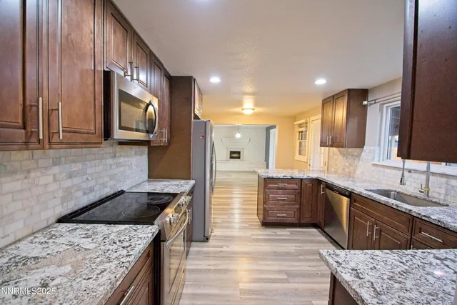 a large kitchen with stainless steel appliances granite countertop a sink stove and refrigerator
