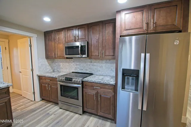 a kitchen with stainless steel appliances granite countertop a refrigerator and a stove top oven