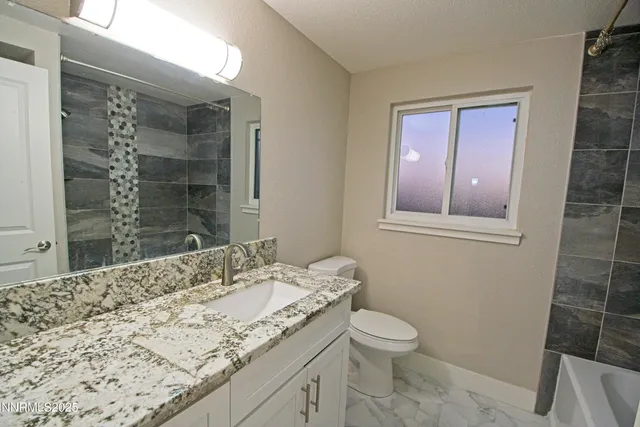 a bathroom with a granite countertop toilet sink and mirror