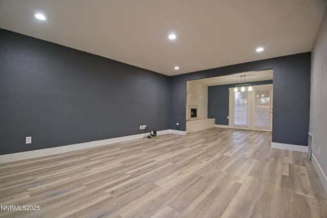 a view of an empty room with wooden floor and windows