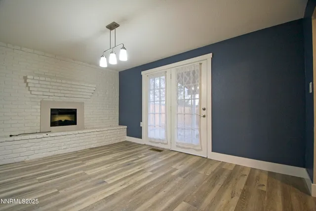 a view of an empty room with wooden floor fireplace and a window