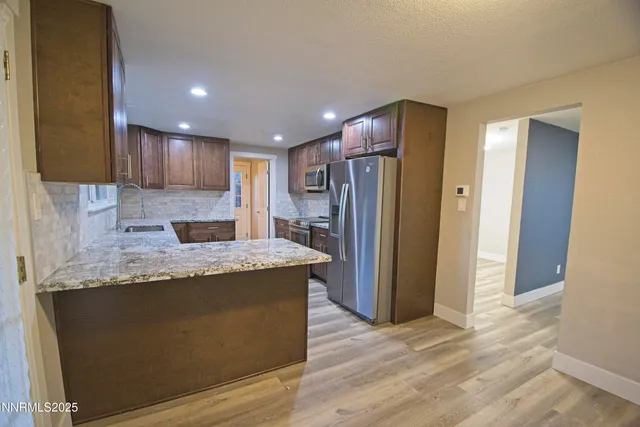 a kitchen with stainless steel appliances granite countertop a refrigerator a sink and a oven